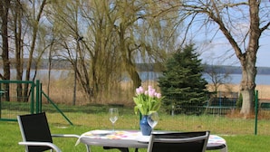 An outdoor seating area with two chairs and a table, a vase with flowers, and a glass of wine. - Holiday Home Reed Path (Warin)