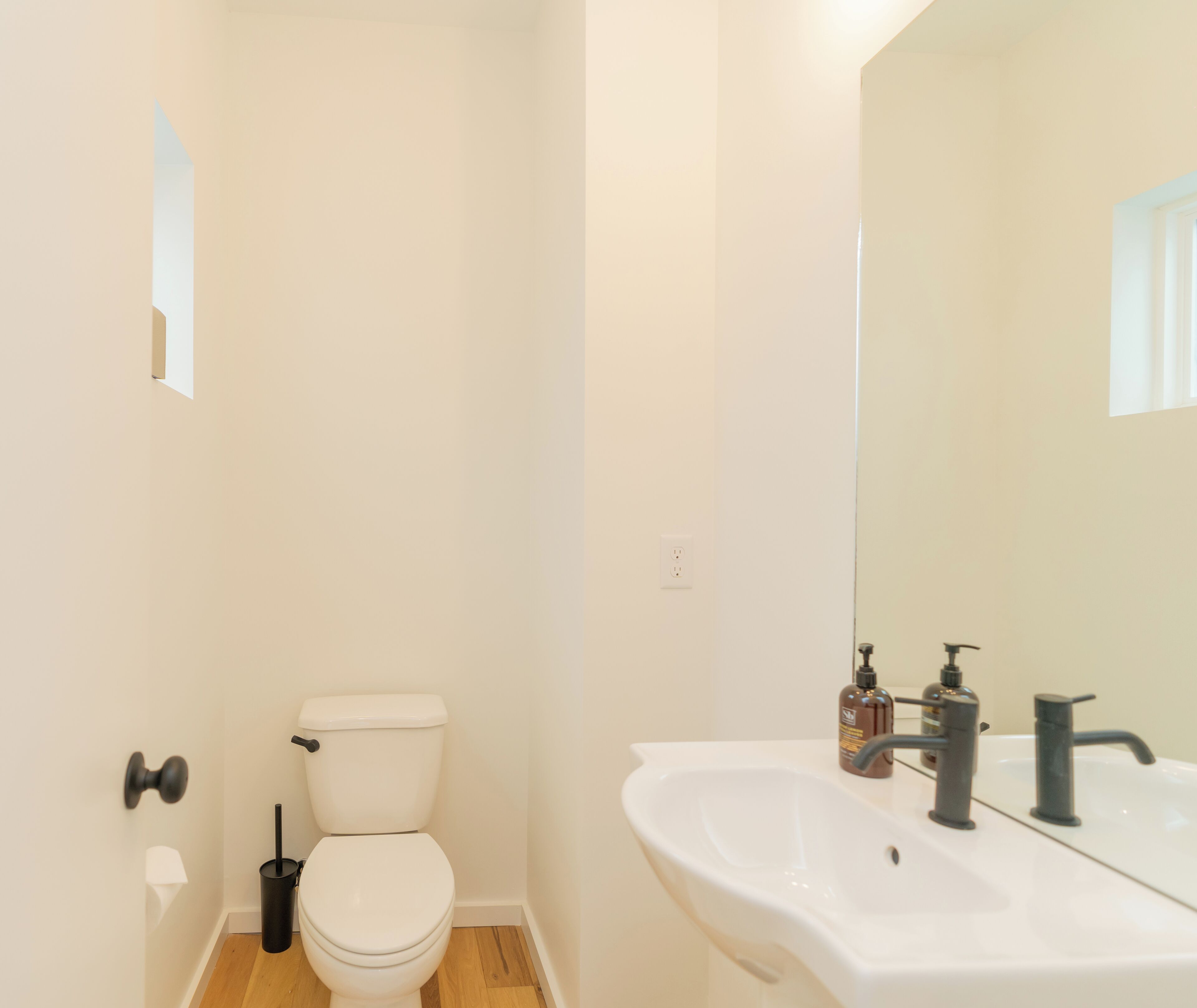 Un baño pequeño y limpio, con inodoro blanco, lavamanos y espejo.