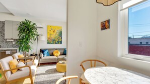 Een moderne woonkamer met een bank, stoelen, een eettafel en een groot raam.