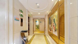 A hotel corridor with a marble floor, a reception desk, and a large painting on the wall. - Vienna Hotel (Shenzhen Gushu Metro Station) (Shenzhen)