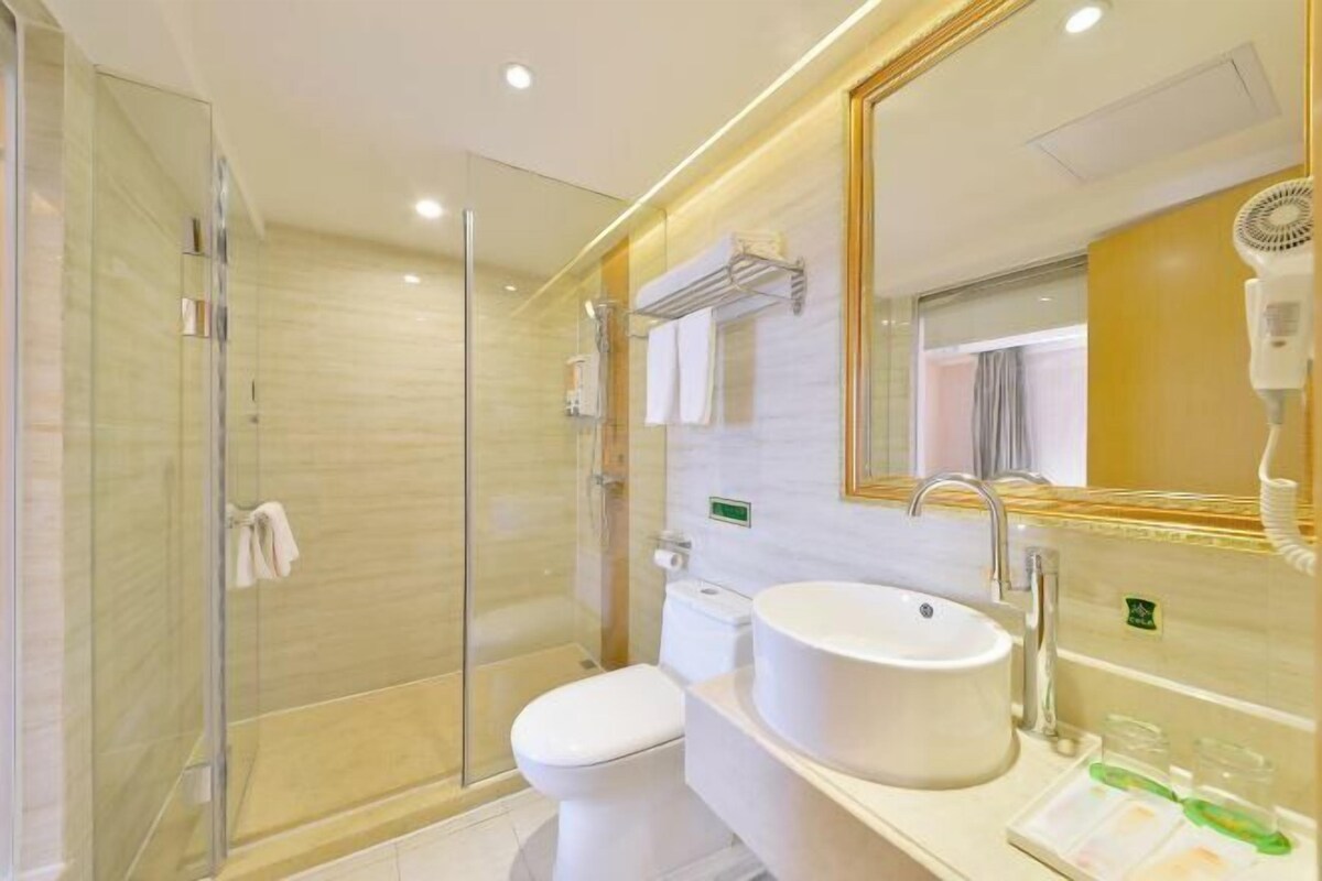 A modern bathroom with a glass-enclosed shower, a white toilet, and a large sink with a mirror above it.