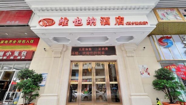 A hotel entrance with a signboard, potted plants, and a red carpet leading to the door. - Vienna Hotel (Shenzhen Gushu Metro Station) (Shenzhen)