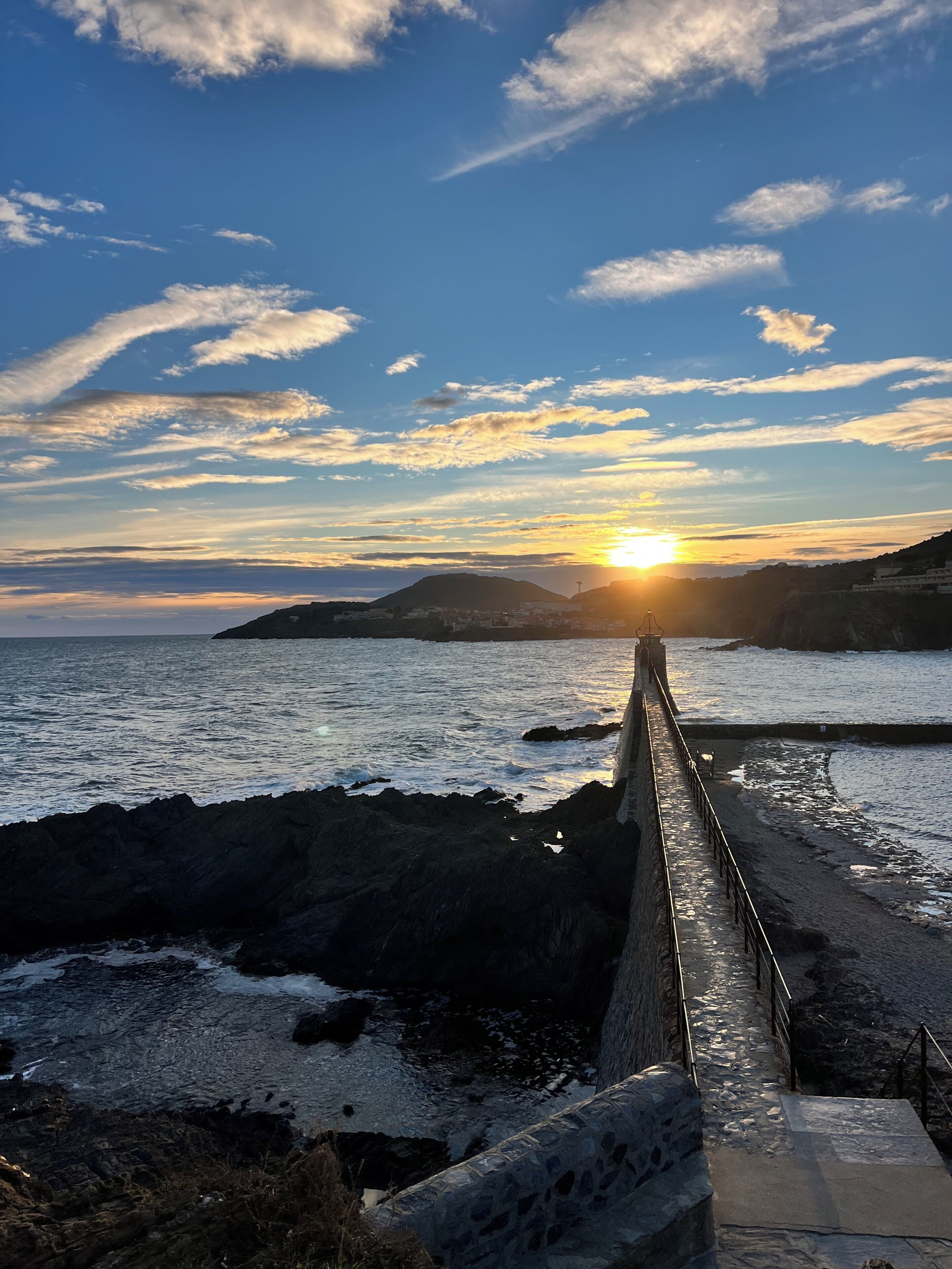 Solnedgang ud til kysten med en stentrappe ned til havet.