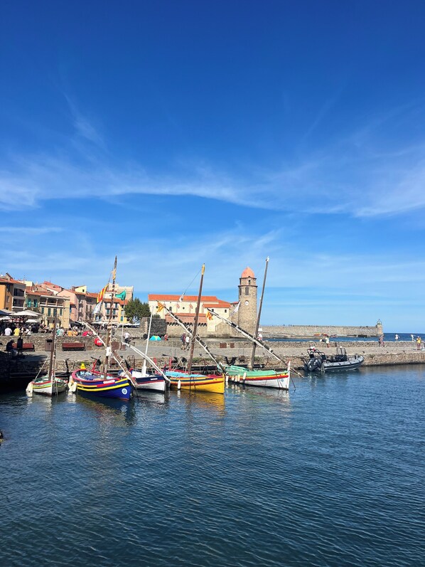 A harbor with boats, a stone wall, and buildings with red roofs. - Appartement Proche de la Mer, Idéal Pour 2 à 4 Personnes, Garage Privé (Collioure)