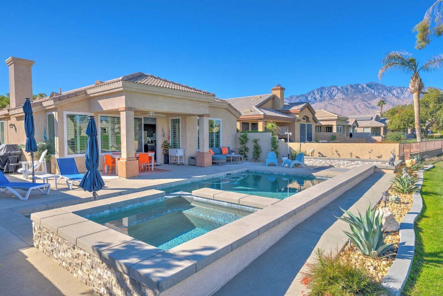 Une propriété résidentielle dotée d’une piscine, d’un espace extérieur aménagé et offrant une vue sur les montagnes.