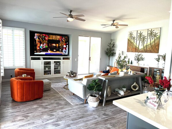 Un salon moderne avec une cheminée, un téléviseur à écran plat et un coin repas agrémenté d’une décoration aux couleurs des fêtes de fin d’année.