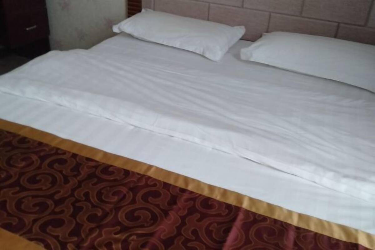A bed with white linens and a patterned bedspread.