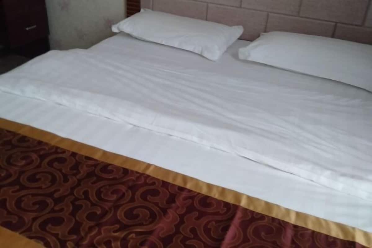 A bed with white linens and a patterned bedspread.