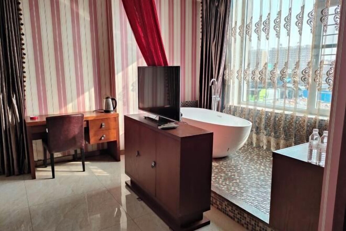 Un baño moderno con bañera, tocador con espejo y televisor sobre un mueble.
