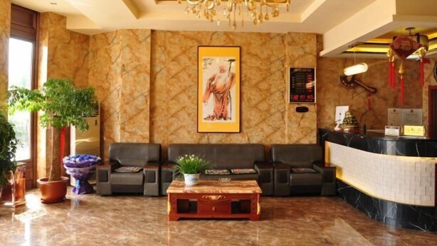 A lobby with a reception desk, two sofas, a coffee table, and a chandelier. - Donggang Xinxiangyuan Hotel (Donggang)