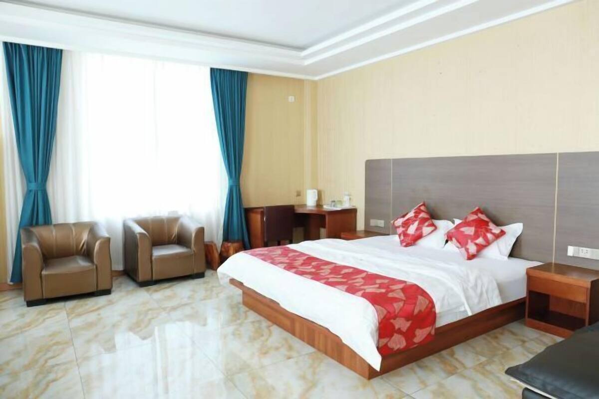 A hotel room with a large bed, two armchairs, a desk, and a nightstand.