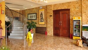 A lobby with a marble floor, a staircase with metal railings, a chandelier, a wooden door, and a vending machine. - Donggang Xinxiangyuan Hotel (Donggang)
