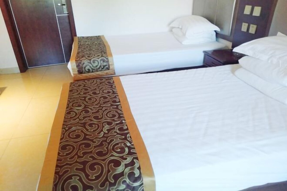 Una habitación de hotel con una cama grande, una mesita de noche y una alfombra estampada.