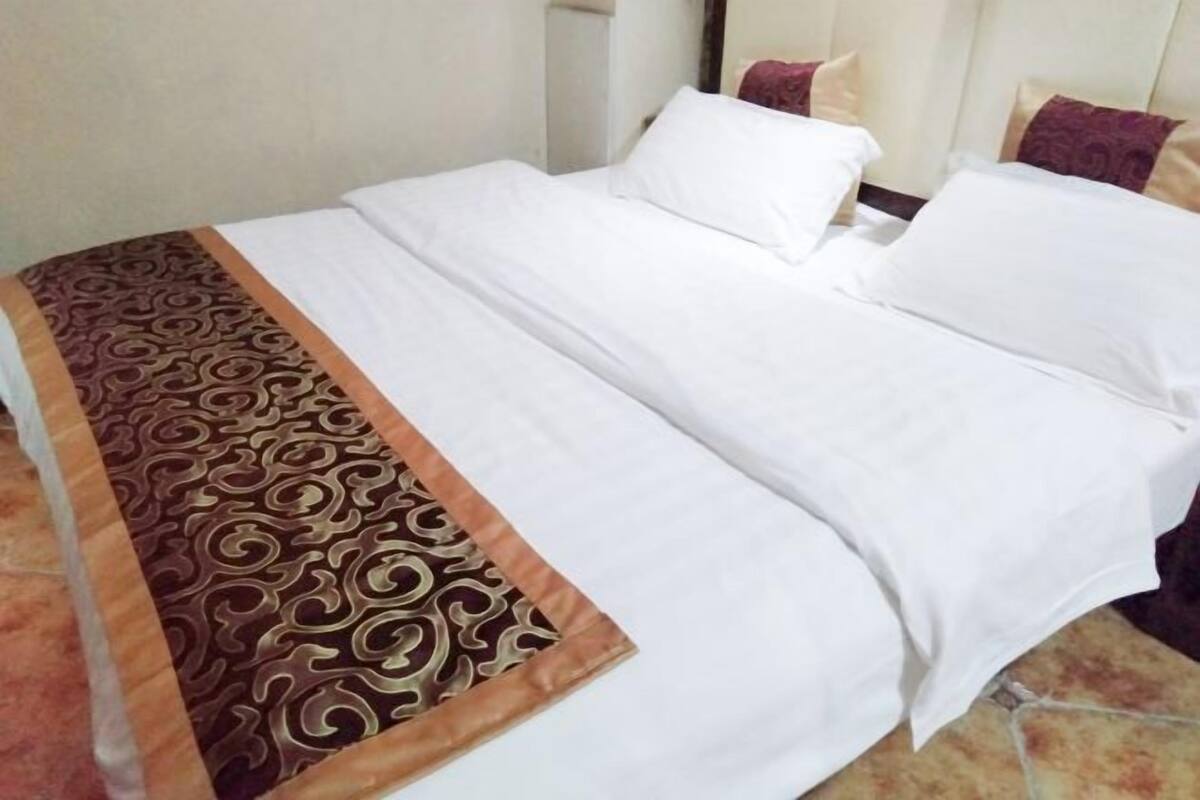 A neatly made bed with white linens and a patterned throw blanket.