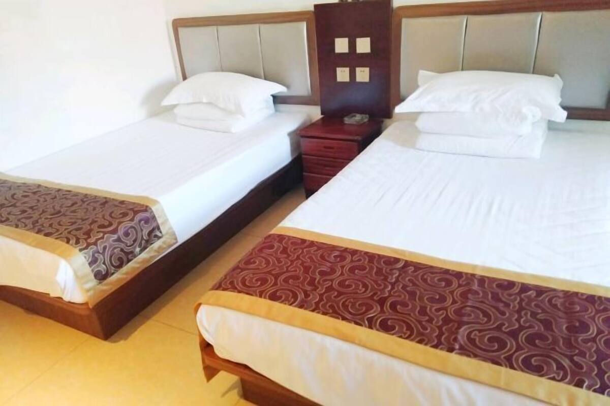 Two single beds with headboards, a wooden nightstand, and a red drawer unit.