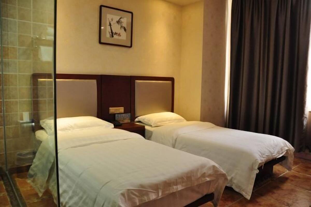 A hotel room with two beds, a shower, and a framed picture on the wall.