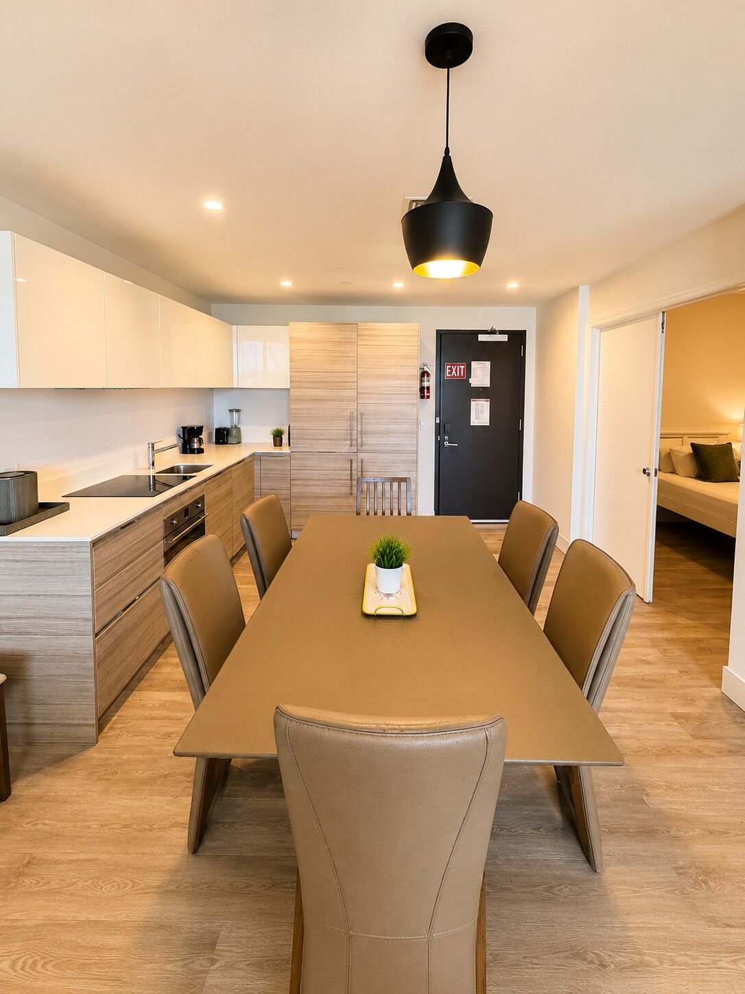 Une cuisine moderne avec un coin repas, comprenant une longue table, des chaises et un luminaire suspendu.