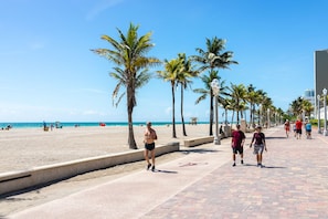 Un paseo marítimo bordeado de palmeras que conduce a la playa.