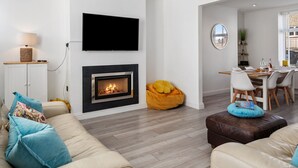 Un salon moderne doté d’une cheminée, d’un téléviseur à écran plat, d  ’un coin repas et d’un espace salon confortable.