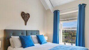 Une chambre à coucher avec un lit, un élément de décoration en forme de cœur sur le mur et une fenêtre avec des rideaux.