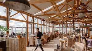 A spacious restaurant with high wooden ceilings and large windows offering views of the sea. - Beach House in Wijk aan Zee With Sea Views (Wijk aan Zee)