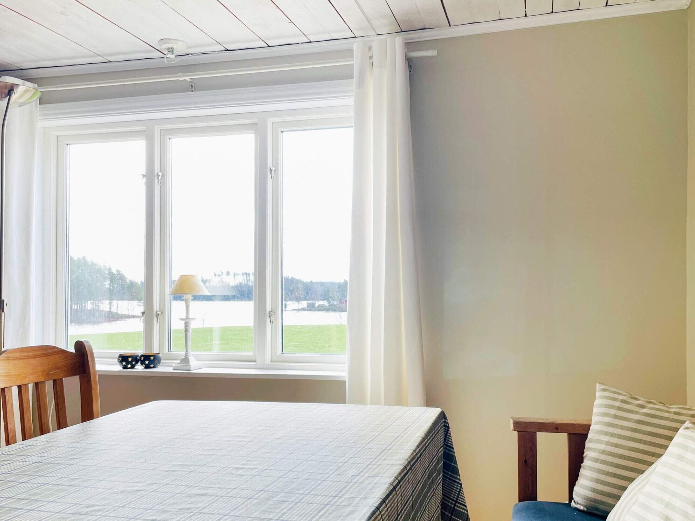 Una habitación con una cama, una silla, una mesa y un ventanal con cortinas.