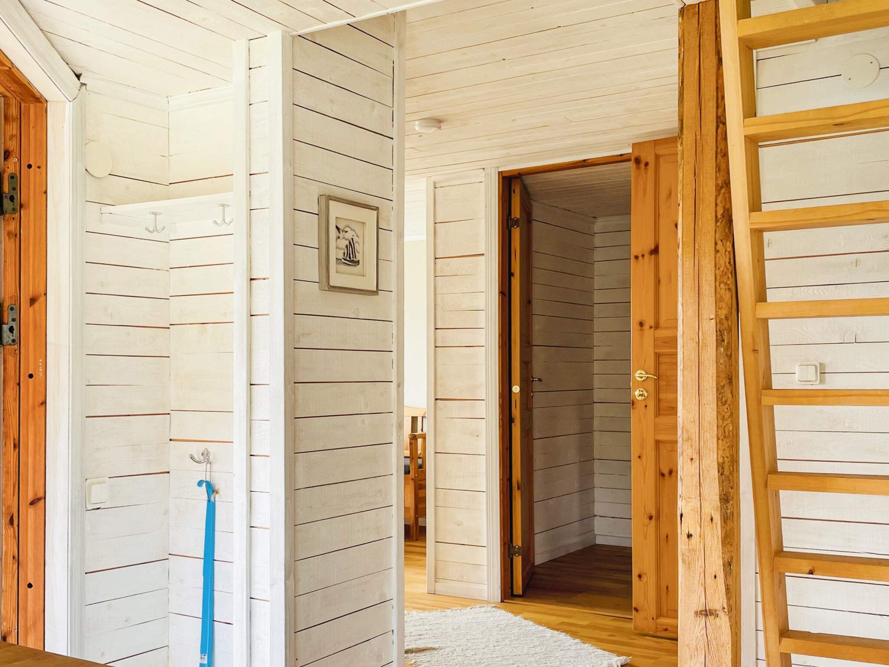 A hallway with wooden walls, a door, and a blue broom leaning against the wall.