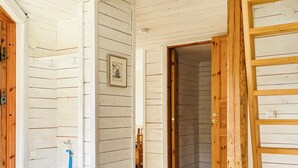 A hallway with wooden walls, a door, and a blue broom leaning against the wall. - 5 Person Holiday Home in Bredared (Bredared)