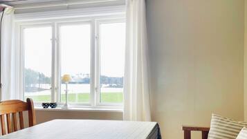 A room with a bed, a chair, a table, and a window with curtains.