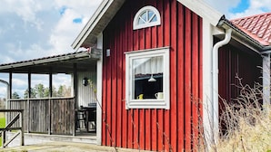 Un bâtiment en bois rouge, doté d’un porche et d’une fenêtre.
