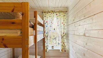 A bunk bed room with a window, a small table, and a curtain with a pattern.