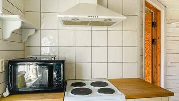 A kitchen with a white stove, a microwave, and a white tiled backsplash.