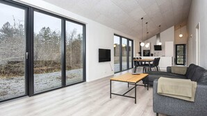 En moderne stue med store skydedøre, et spiseområde og et køkken.