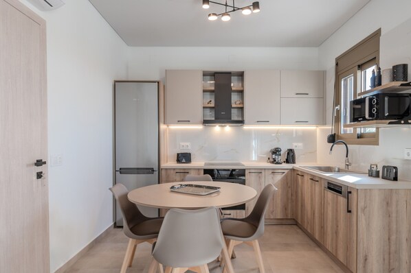 A modern kitchen with a round dining table, built-in appliances, and a minimalist design. - Meli & Gio 1 villa,private pool, near tavern,Rethymno (Viran Episkopi)