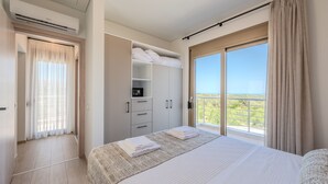 A bedroom with a large bed, a wardrobe, a built-in heater, and a balcony with a view. - Meli & Gio 1 villa,private pool, near tavern,Rethymno (Viran Episkopi)