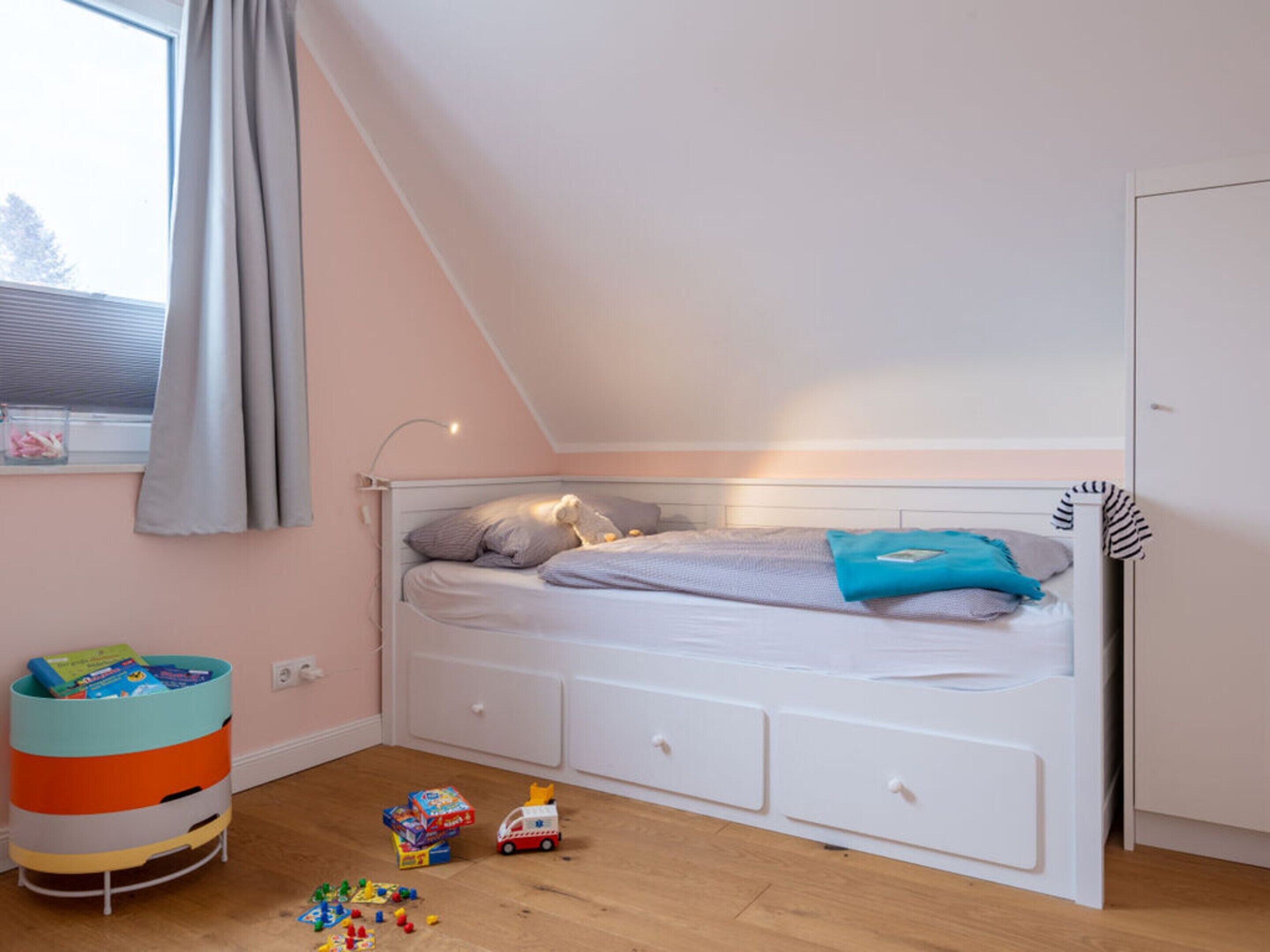 Una habitación infantil con literas, un coche de juguete y un cesto de almacenamiento.