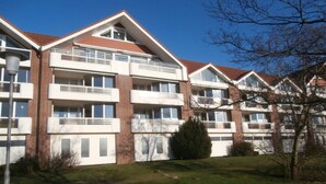 Un immeuble résidentiel à plusieurs étages, doté de balcons et d’une façade en briques, avec un ciel dégagé.