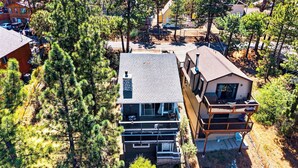 A multi-story house with a balcony, surrounded by trees. - Mountain Palette by Avantstay Hot Tub, Game Room, Deck, Sweeping Views! (Big Bear City)