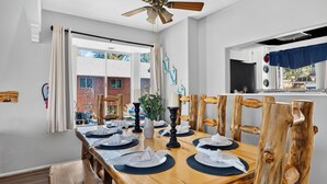 A dining area with a wooden table, chairs, and a ceiling fan. - Mountain Palette by Avantstay Hot Tub, Game Room, Deck, Sweeping Views! (Big Bear City)