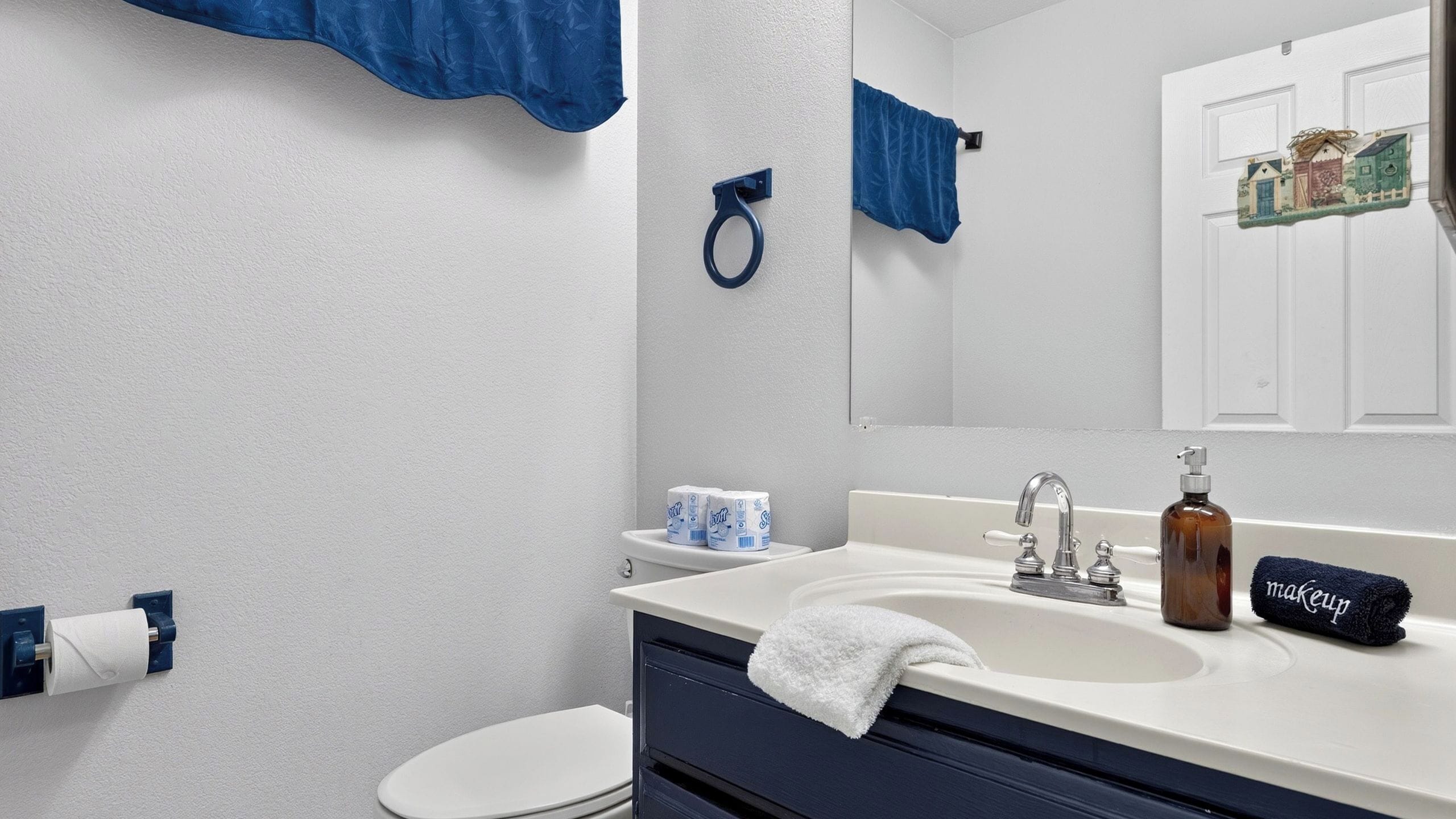A bathroom with a white toilet, a sink with a mirror, and a towel rack.