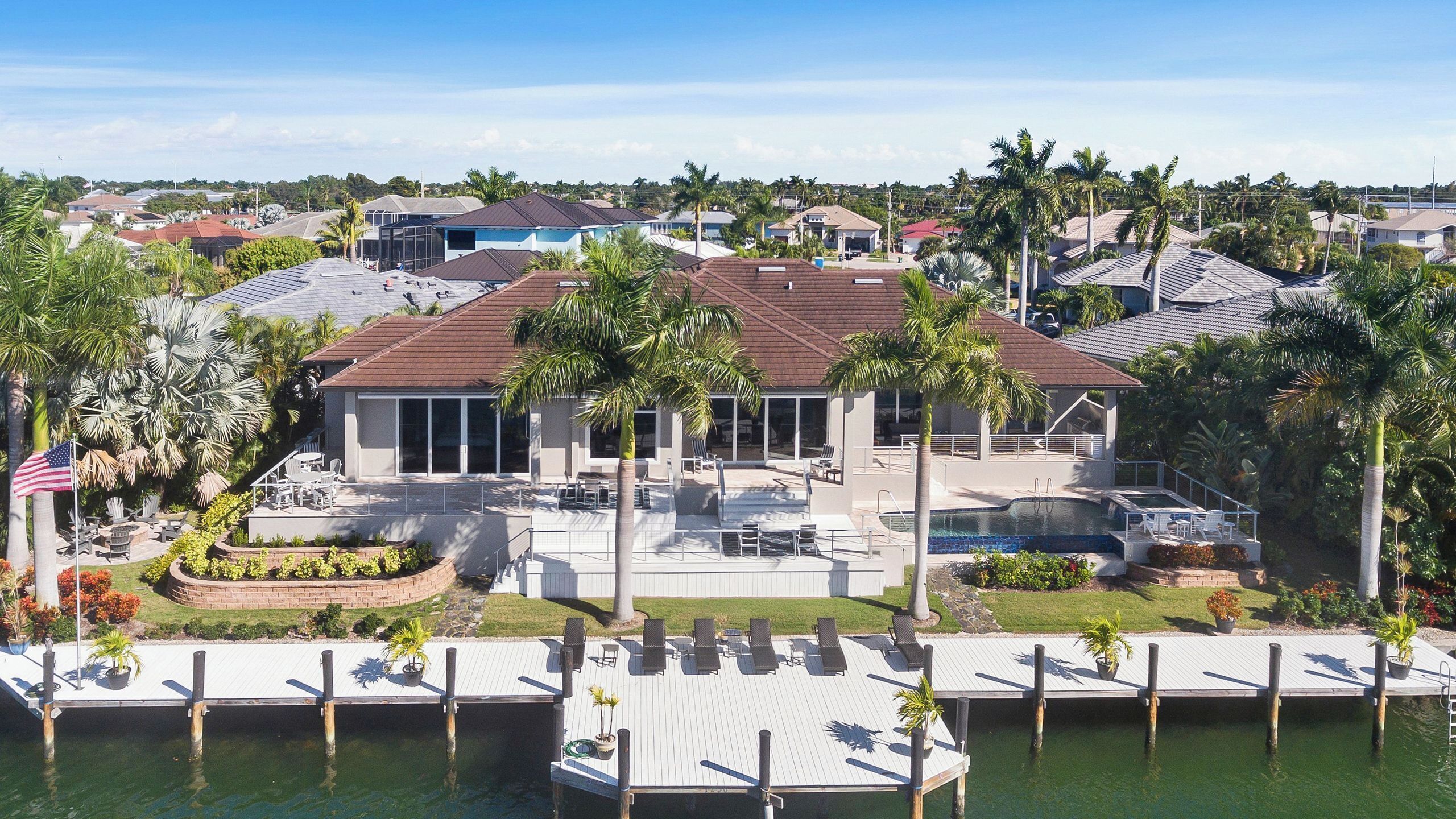 A residential property with a swimming pool, outdoor seating, and a dock.