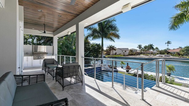 A covered outdoor area with a pool, patio furniture, and a view of the water.