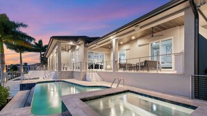 A modern house with a swimming pool, large windows, and a covered patio area.