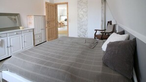 A bedroom with a bed, a chair, a dresser, and a mirror. - Holiday Apartment Mozartmansarde (Waren (Müritz))