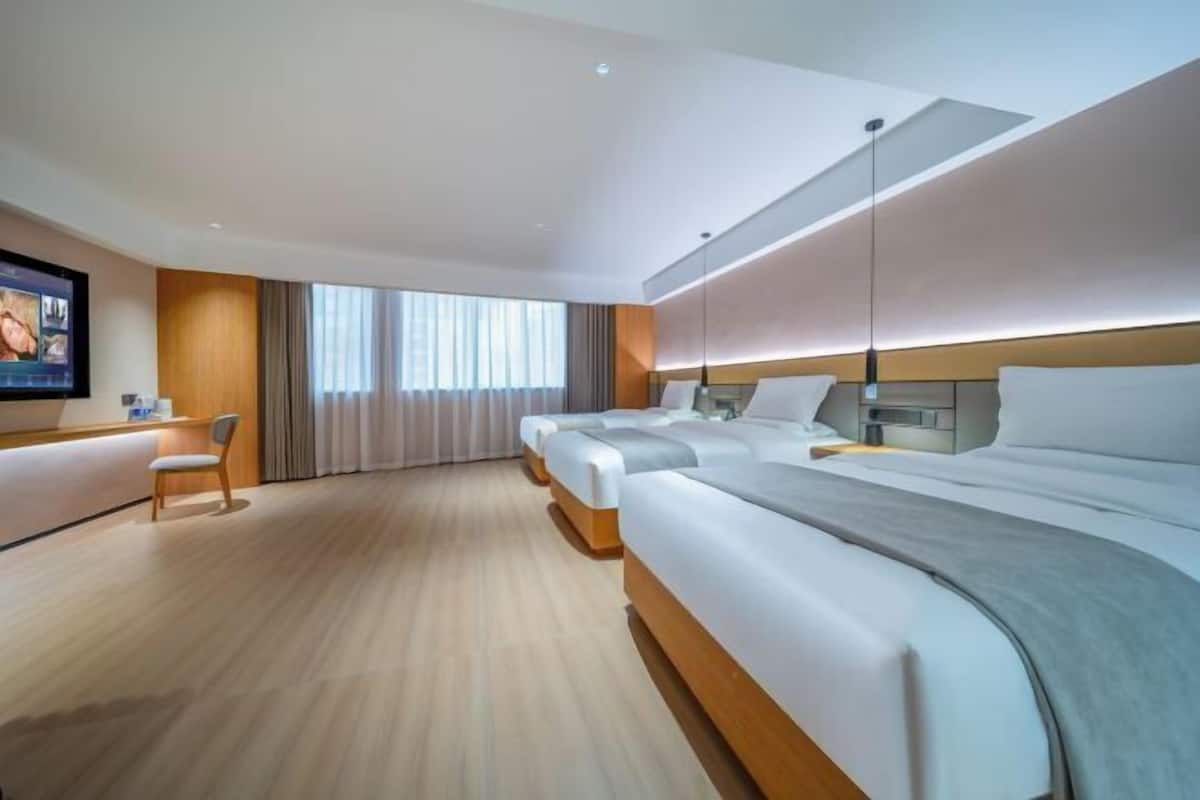 Quarto de hotel moderno com uma cama grande, uma escrivaninha e uma televisão.