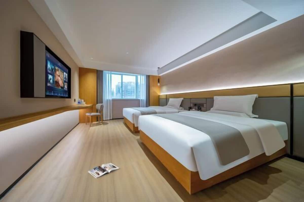 Quarto de hotel moderno com uma cama grande, uma escrivaninha e uma TV fixada na parede.