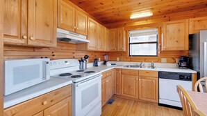 Una cocina con armarios de madera, estufa, microondas, pileta y refrigerador.