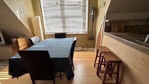 A dining area with a table and chairs, a window with blinds, a floor lamp, and a view of the kitchen. - Great Asheville Location (Asheville)
