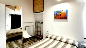 Ein Schlafzimmer mit einem Bett, einem Sessel, einem Heizkörper, einer Leiter und einem Bild an der Wand.