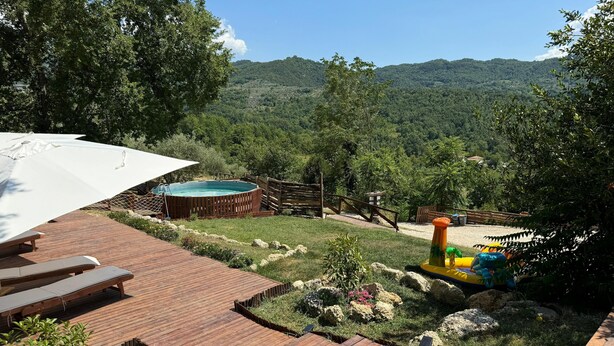 Eine Holzterrasse mit Liegestühlen, einem Whirlpool und einem Spielbereich für Kinder mit aufblasbaren Spielzeugen.